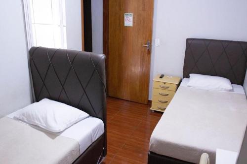 Habitación con 2 camas y suelo de madera. en Pousada Castelo Branco, en Arapongas
