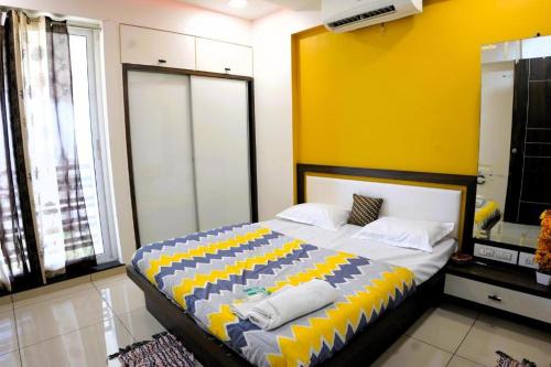 ein Schlafzimmer mit einem großen Bett mit gelber Wand in der Unterkunft Fortune Penthouse 11th floor with sky orbit swimming pool and gym in Rajkot