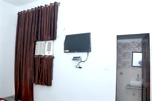 baño con TV en la pared en Shree Banzaara Dham en Pātolī