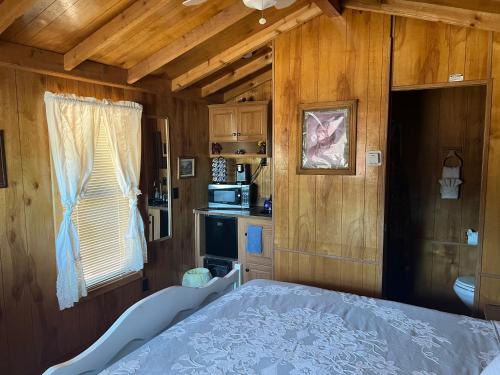a bedroom with a bed and a kitchen with wooden walls at Stampede RV B&B in Tombstone