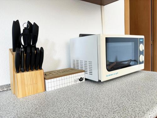 a microwave and a block of knives next to a microwave at Incanto Nesso Parking and Lake View in Nesso