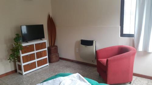 salon z czerwonym krzesłem i telewizorem w obiekcie Loma del Alto w mieście Alta Gracia