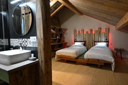- une chambre avec 2 lits, un lavabo et un miroir dans l'établissement Bienvenue Au Grand Cœur Chaux, à Guyans-Vennes