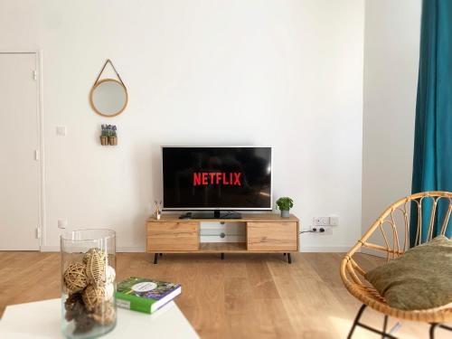 - un salon avec une télévision sur un support en bois dans l'établissement Appartement centre-ville cosy WIFI et Netflix, à Fontenay-le-Comte