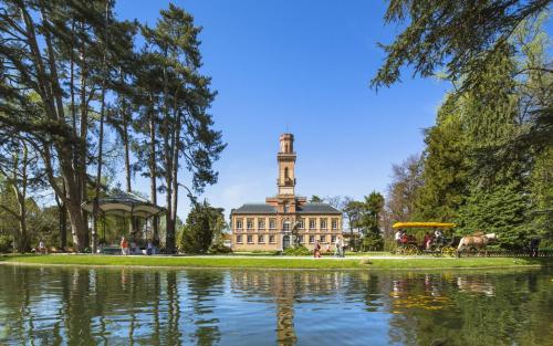un bâtiment avec une tour d'horloge en face d'un étang dans l'établissement Charmant T2 avec grande terrasse quartier Jardin Massey, à Tarbes