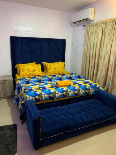 Una cama azul con almohadas amarillas en una habitación en Jesam House, en Suru Lere