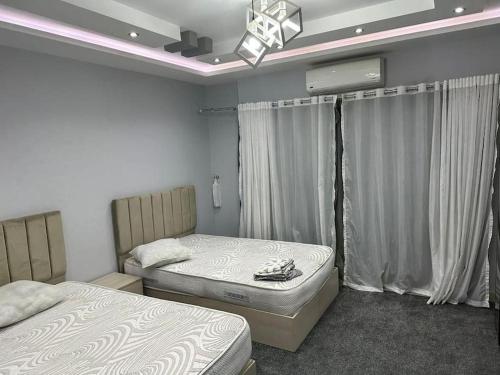 カイロにある3 bedroom apartment, Sheraton Al Matar, Nozhaのベッドルーム1室(ベッド2台付)、窓(カーテン付)