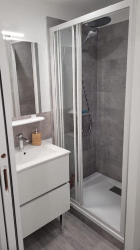 La salle de bains est pourvue d'une douche et d'un lavabo blanc. dans l'établissement Appartement plein Centre Cauterets, Vacances et Cures, à Cauterets