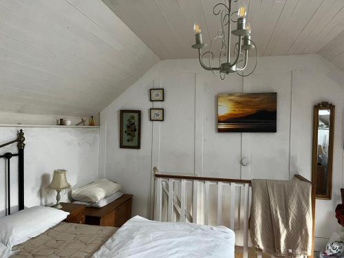 1 dormitorio con 2 camas y lámpara de araña en 3 bed cottage in Ahakista West cork en Ahakista