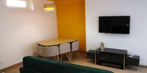 uma sala de estar com um sofá verde, uma mesa e uma televisão em La promesse - T3 Hyper centre em Abbeville