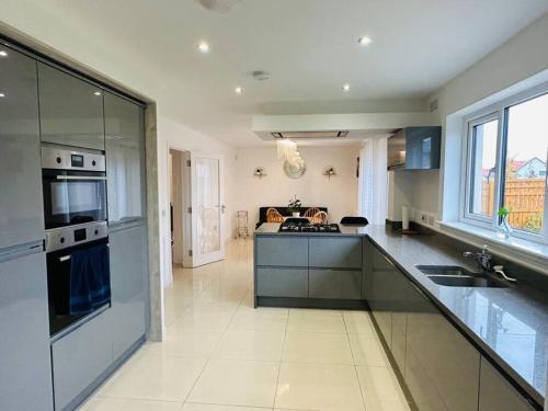 a large kitchen with a sink and a stove at 5 Bedroom detached House near Edinburgh Airport, City center and Murrayfield Stadium in East Calder
