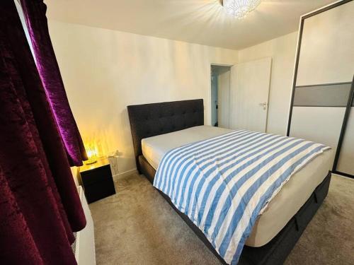 a bedroom with a bed with a blue and white striped blanket at 5 Bed Detached House near Edinburgh Airport in East Calder