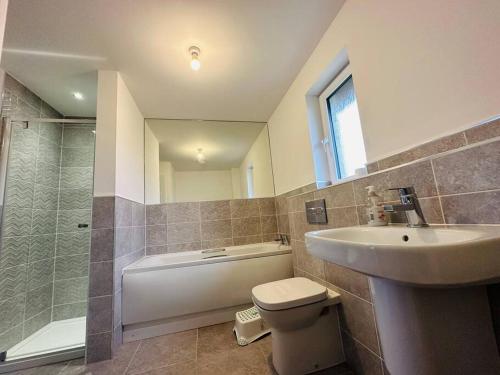 uma casa de banho com um lavatório, um WC e um chuveiro em Modern new build detached House near Edinburgh Airport em East Calder