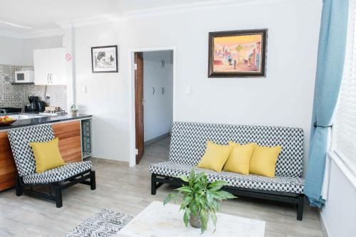 a living room with two chairs and a couch with yellow pillows at Edwil's Place in Hartbeespoort