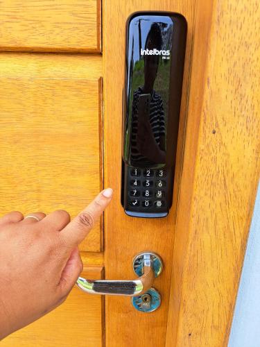a person pointing at a cell phone on a door at Embahu Suítes - Vista para Pedra do Baú e banheira de imersão in Santo Antônio do Pinhal