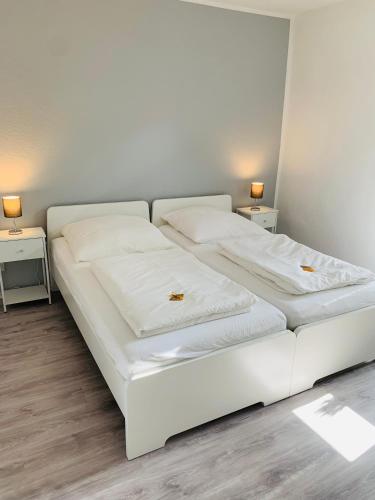 a white bed in a room with two side tables at Blaue 8 in Rampe