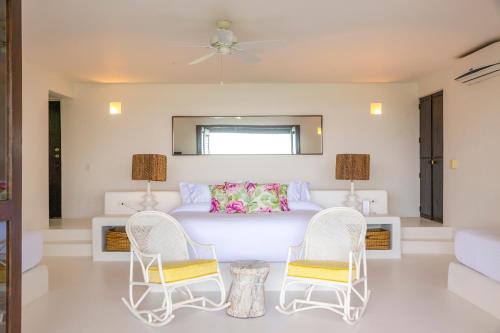a bedroom with a white bed and two chairs at Hotel Agua Baru by Mustique in Baru