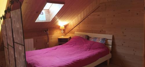 - une chambre avec un lit violet dans une cabane en bois dans l'établissement Appart La Porte des Neiges - Saint Jean de Sixt (La Clusaz, Le Grd Bornand), à Saint-Jean-de-Sixt