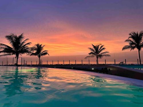 een zwembad met palmbomen voor de zonsondergang bij Best Ocean View in The Gambia! in Sere Kunda