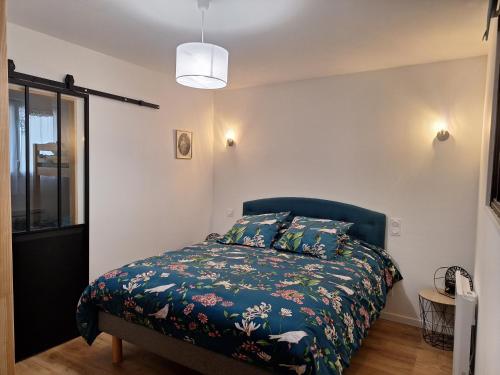 a bedroom with a bed with a floral bedspread at La perle de Houlgate in Houlgate