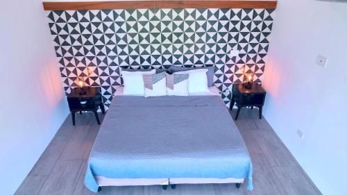 Tropical Loft Home - Ocean View في سان خوان ديل سور: غرفة نوم مع سرير وطاولتين مع مصابيح