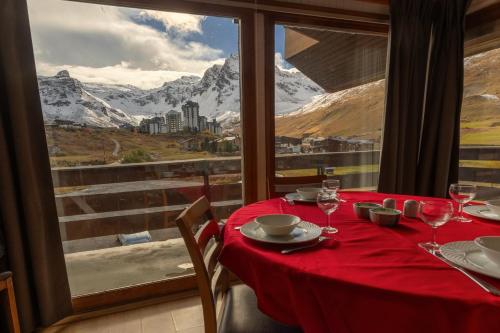 a table with a red tablecloth and wine glasses and a window at Duplex 65 m2 au coeur du golf de Tignes in Tignes