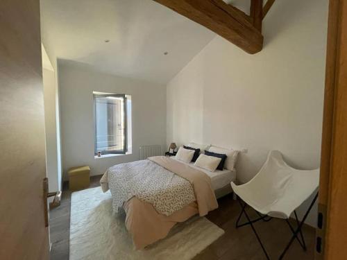 - une chambre blanche avec un lit et une chaise dans l'établissement Beaujolais - Maison pierres dorées, à Ville-sur-Jarnioux