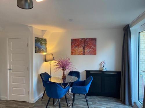 a dining room with a table and blue chairs at Homely, Cosy & Contemporary 4 BDR house with Garden & Parking 5 mins drive to Addenbrookes & Papworth hospitals & Bio Medical campus in Cambridge