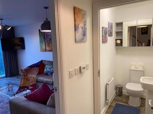 a bathroom with a toilet and a couch in a room at Homely, Cosy & Contemporary 4 BDR house with Garden & Parking 5 mins drive to Addenbrookes & Papworth hospitals & Bio Medical campus in Cambridge