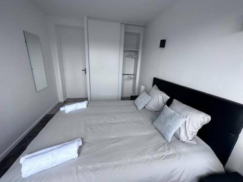 Elle comprend un grand lit avec des draps et des oreillers blancs. dans l'établissement Accès rapide à Paris & Disney avec parking, à Maisons-Alfort