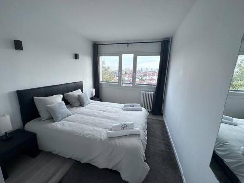 a bedroom with two beds and a large window at F3 au bord de la Marne, à deux pas de Paris +Box ! in Maisons-Alfort