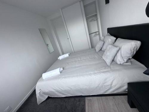 un lit avec des draps blancs et des oreillers dans une chambre dans l'établissement Accès rapide à Paris & Disney avec parking, à Maisons-Alfort