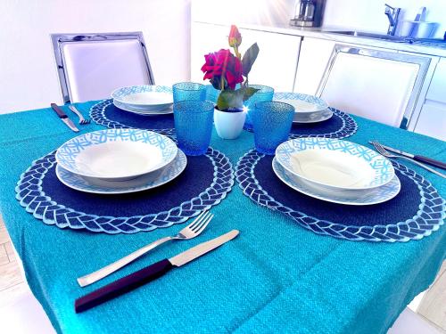 a table with plates and utensils on a blue table cloth at Alloggio Ulivi in Isola Rossa