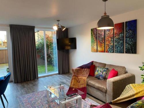 a living room with a couch and a glass table at Homely, Cosy & Contemporary 4 BDR house with Garden & Parking 5 mins drive to Addenbrookes & Papworth hospitals & Bio Medical campus in Cambridge