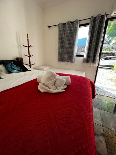 a bedroom with a bed with a red blanket at Pousada Novo Encanto Maresias in Maresias