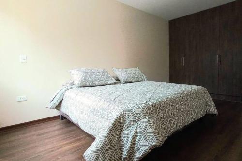 een slaapkamer met een bed met een dekbed en kussens bij La Carolina 202 Bello Departamento in Quito
