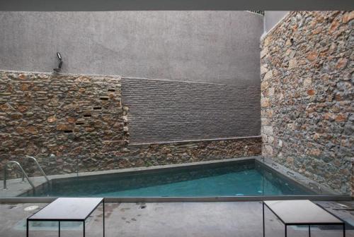 a swimming pool in a room with a stone wall at Art Hotel Athens in Athens