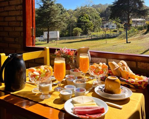 uma mesa com comida e copos de sumo de laranja em Chalés Recanto da cachoeira em Monte Verde