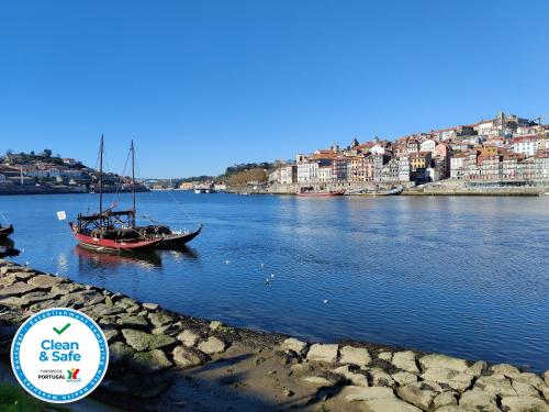a boat in a river with a city in the background at Cais de Gaia Historic Loft in Vila Nova de Gaia