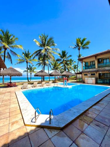 a swimming pool at the resort with palm trees at Beira Mar Porto de Galinhas Hotel in Porto De Galinhas