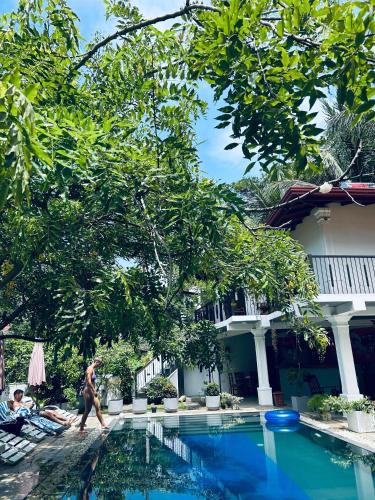 a man walking by a swimming pool in front of a house at Villa Red Lobster in Hikkaduwa