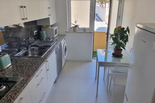 a kitchen with white cabinets and a sink and a table at Apartamento Palomar in Pombal