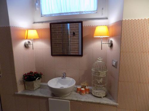 La salle de bains est pourvue d'un lavabo, de deux lumières et d'un miroir. dans l'établissement Il Giardino del Viaggiatore, à Rome