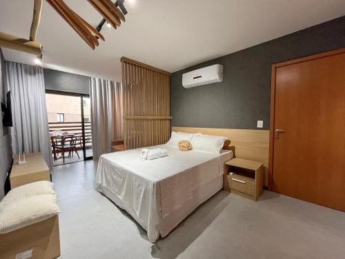 a bedroom with a white bed and a table at Excelente condomínio com uma belíssima área de lazer próximo à praia do Patacho in Pôrto de Pedras