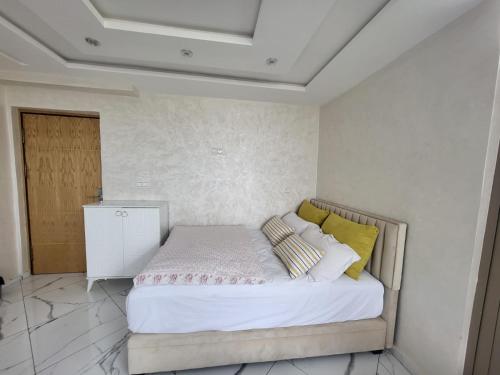 Schlafzimmer mit einem Bett mit weißer Bettwäsche und gelben Kissen in der Unterkunft Modern Studio Just Steps from the Beach in El Jadida