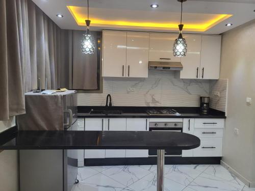 a kitchen with white cabinets and a black counter top at Modern Studio Just Steps from the Beach in El Jadida