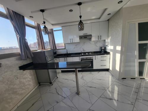 een keuken met witte kasten en een zwart aanrecht bij Modern Studio Just Steps from the Beach in El Jadida