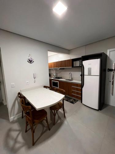 a kitchen with a table and a white refrigerator at Seu refúgio a 250 metros do mar. in Governador Celso Ramos