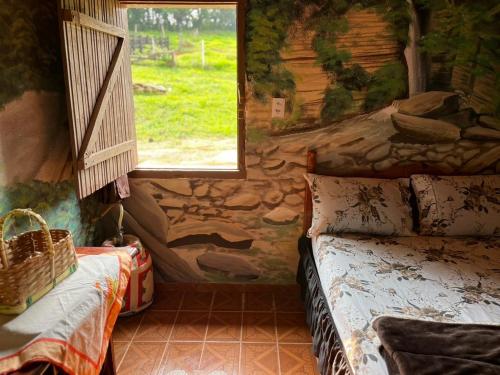 - une chambre dotée d'un mur en pierre avec un lit et une fenêtre dans l'établissement Sitio da Mata, à São Thomé das Letras