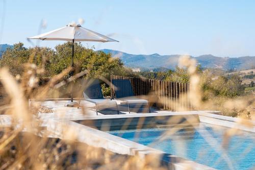 a swimming pool with an umbrella and chairs next to at Casa do Vale in Marvão